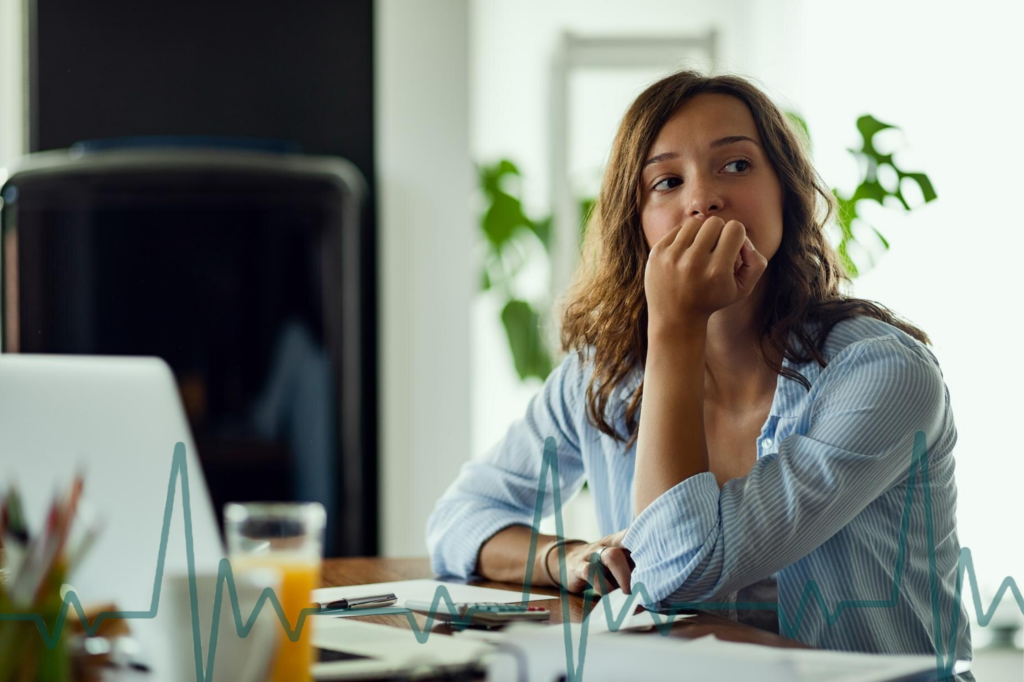 a woman sits at a table experiencing stress-related arrythmia