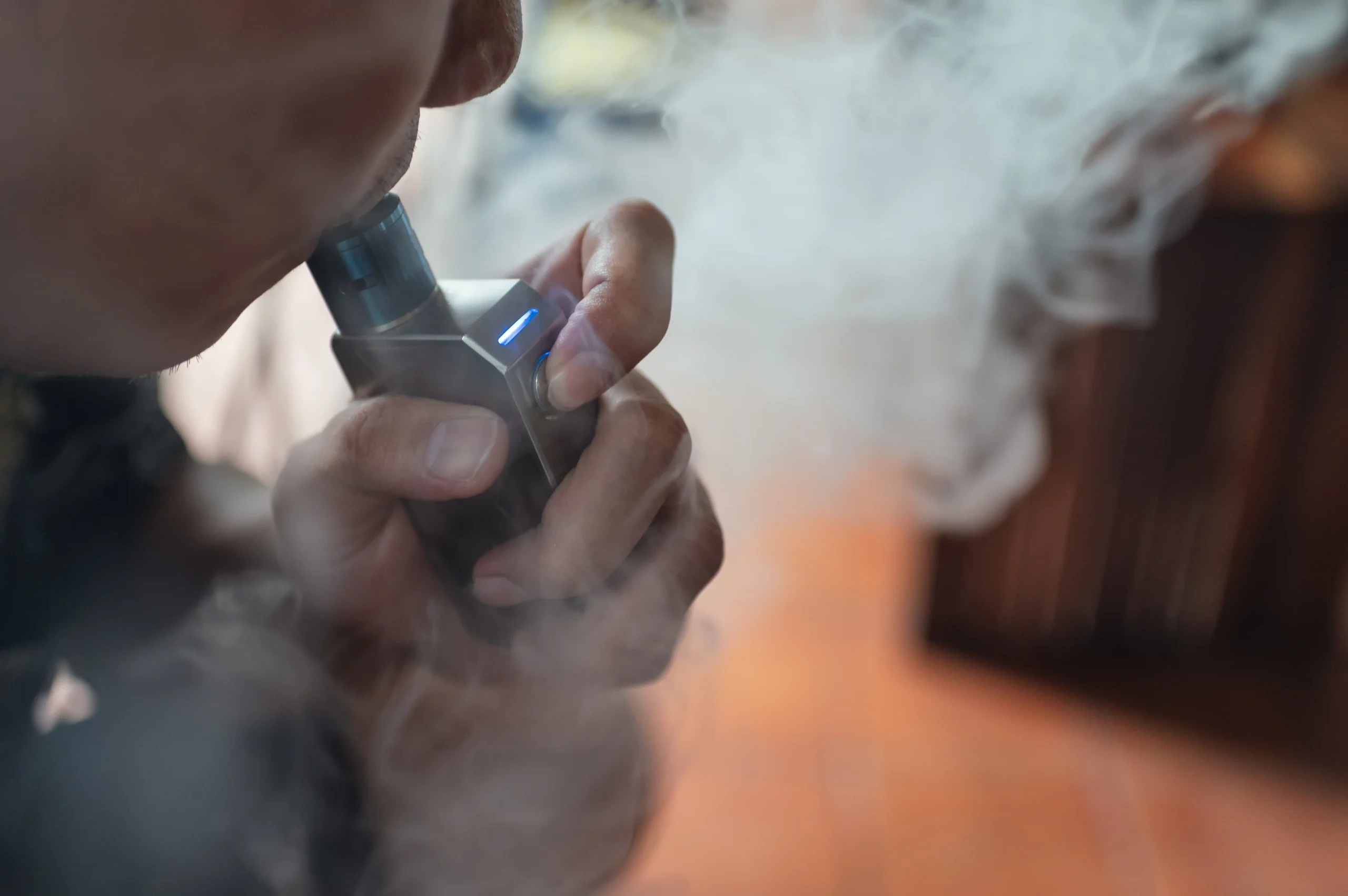a man exhales vapor from an e-cigarette vape